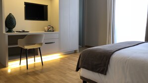 Un dormitorio moderno con una cama, un escritorio con silla y una televisión.