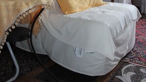 A cozy room with a white armchair, a small table with a yellow cloth, a bookshelf, and a lamp. - B&B Il Ciottolo (Genoa)