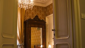 A bedroom with a large bed, a chandelier, and a mirror. - B&B Il Ciottolo (Genoa)