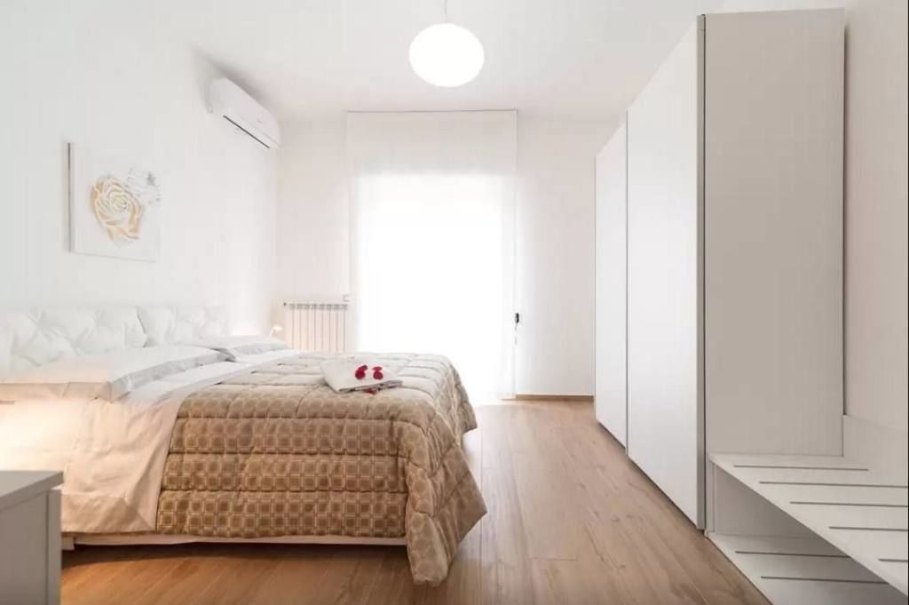 A bedroom with a bed, a bedside table, a wardrobe, and a radiator.