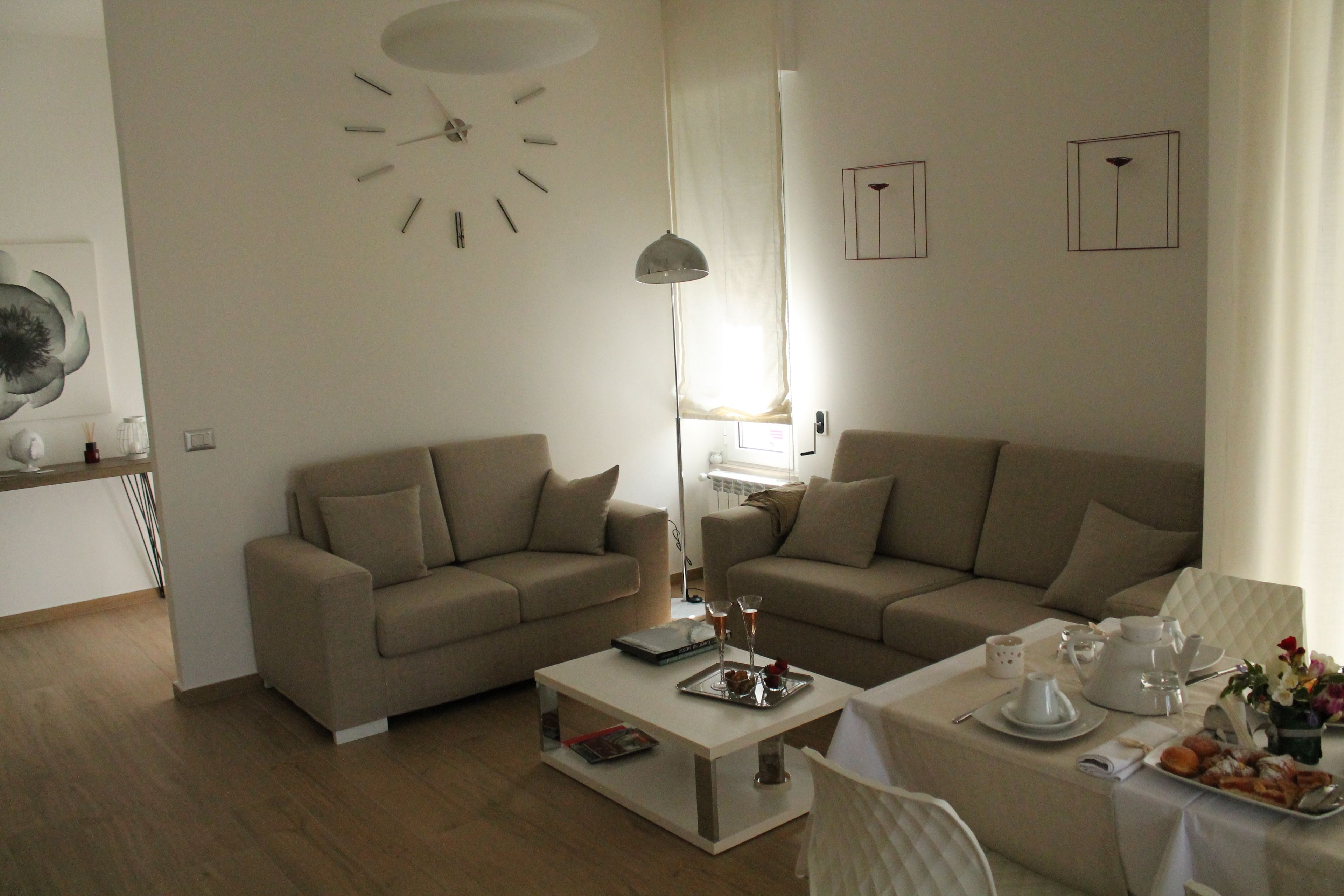 Un salon moderne avec deux canapés beige, une table basse blanche et un coin repas avec une table dressée pour deux personnes.