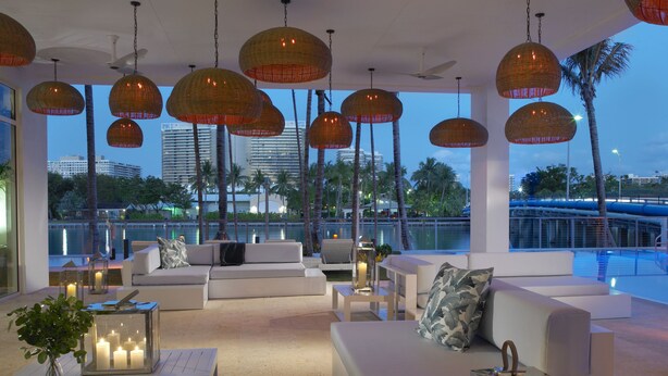 A modern lounge area with white sofas, a pool, and hanging wicker lamps. - Grand Beach Hotel Bay Harbor (Bay Harbor Islands)