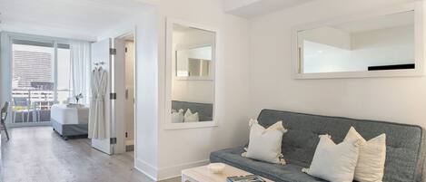 Un salon moderne avec un canapé gris, une table basse et un grand miroir au mur.