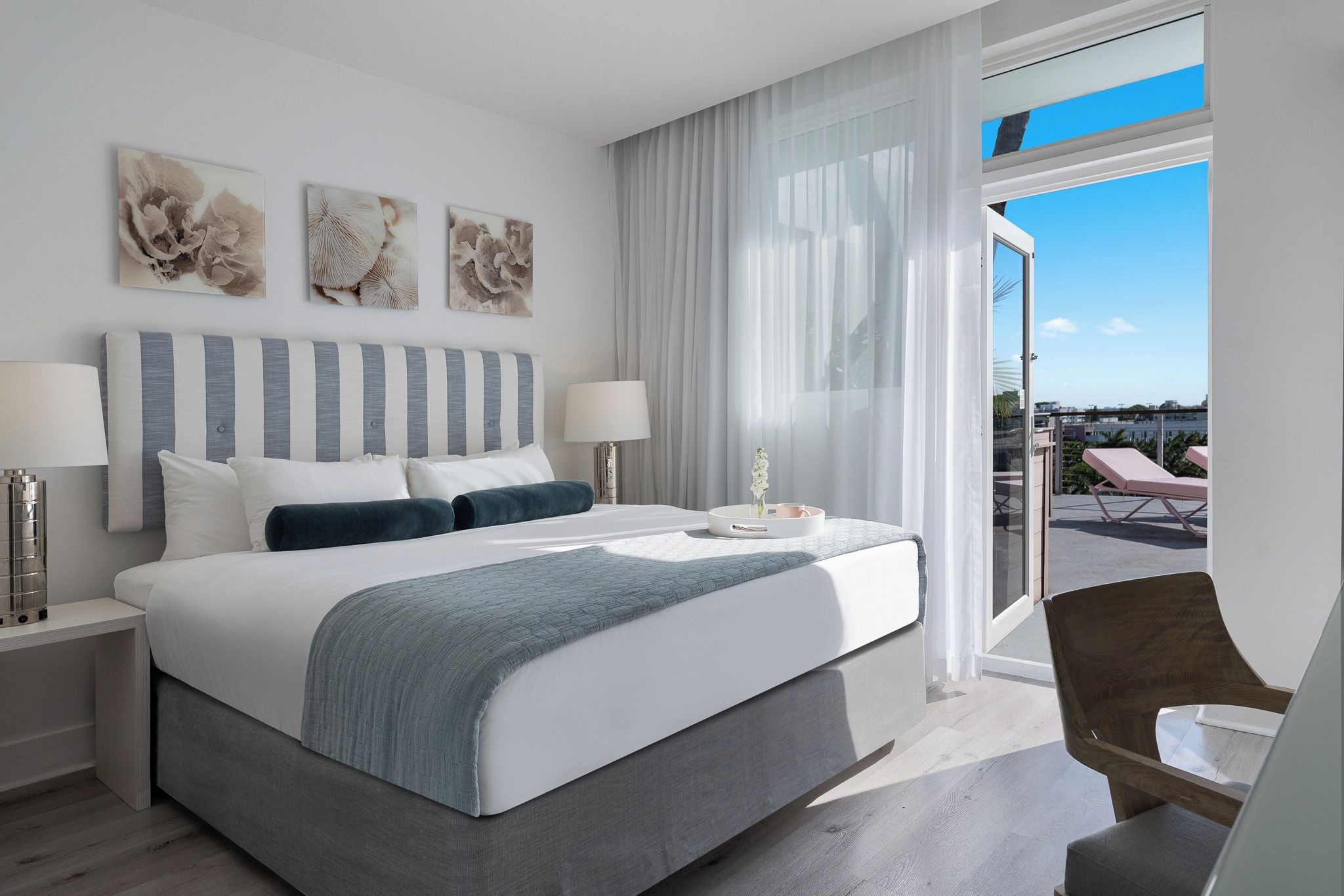 Ein modernes Hotelzimmer mit einem großen Bett, zwei Nachttischen, einem Schreibtisch und Blick ins Freie.