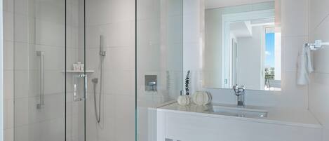 A modern bathroom with a glass-enclosed shower, a large mirror, and a white vanity.