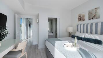 Ett modernt hotellrum med en säng, ett sängbord, en stol och utsikt över korridoren.