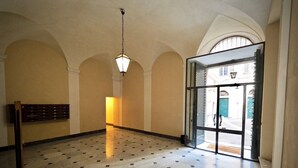 Un hall d’entrée spacieux, doté d’un sol carrelé, d’un luminaire suspendu et d’une grande porte vitrée donnant sur l’extérieur.