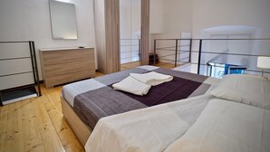 Une chambre moderne avec un lit, une commode, un miroir et un balcon doté d’une balustrade.