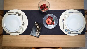 Une table à manger dressée avec des assiettes, des couverts et deux bols remplis de nourriture.