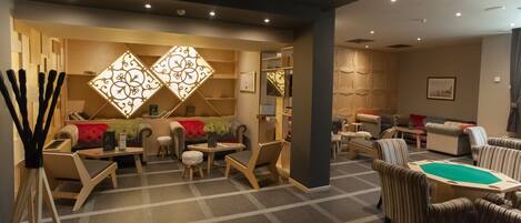 A modern lounge area with sofas, chairs, and a pool table.