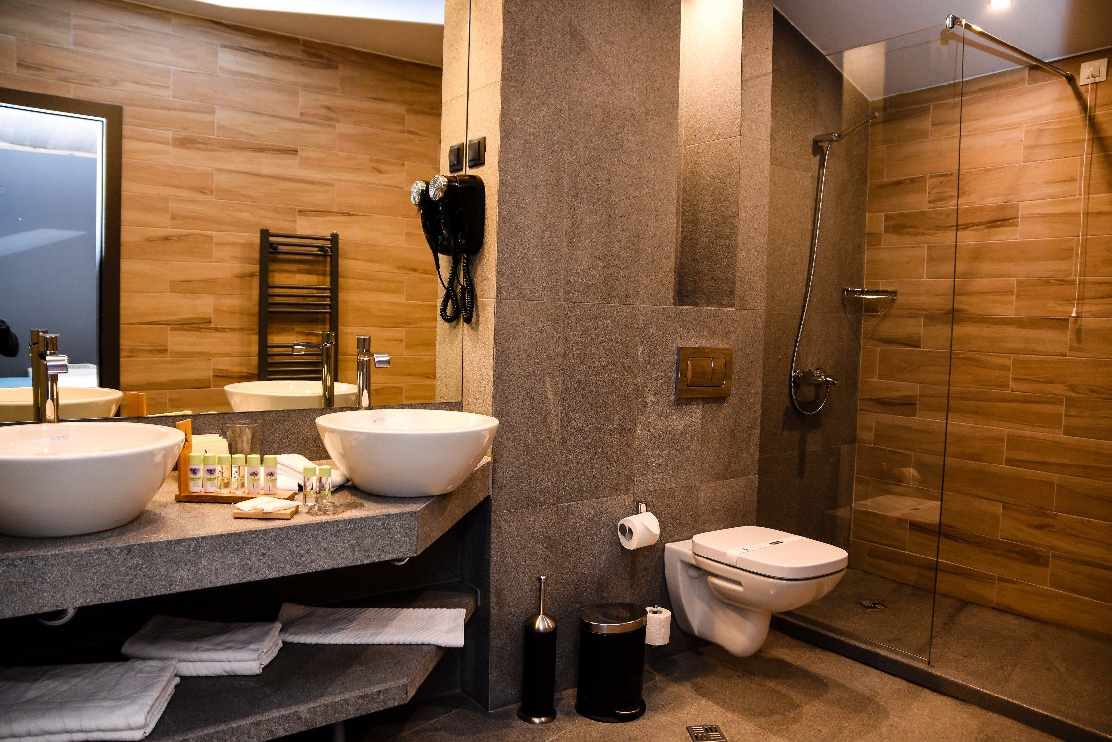 A modern bathroom with two sinks, a toilet, and a shower.