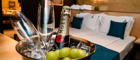 Un minibar con una botella de champán, copas y uvas.