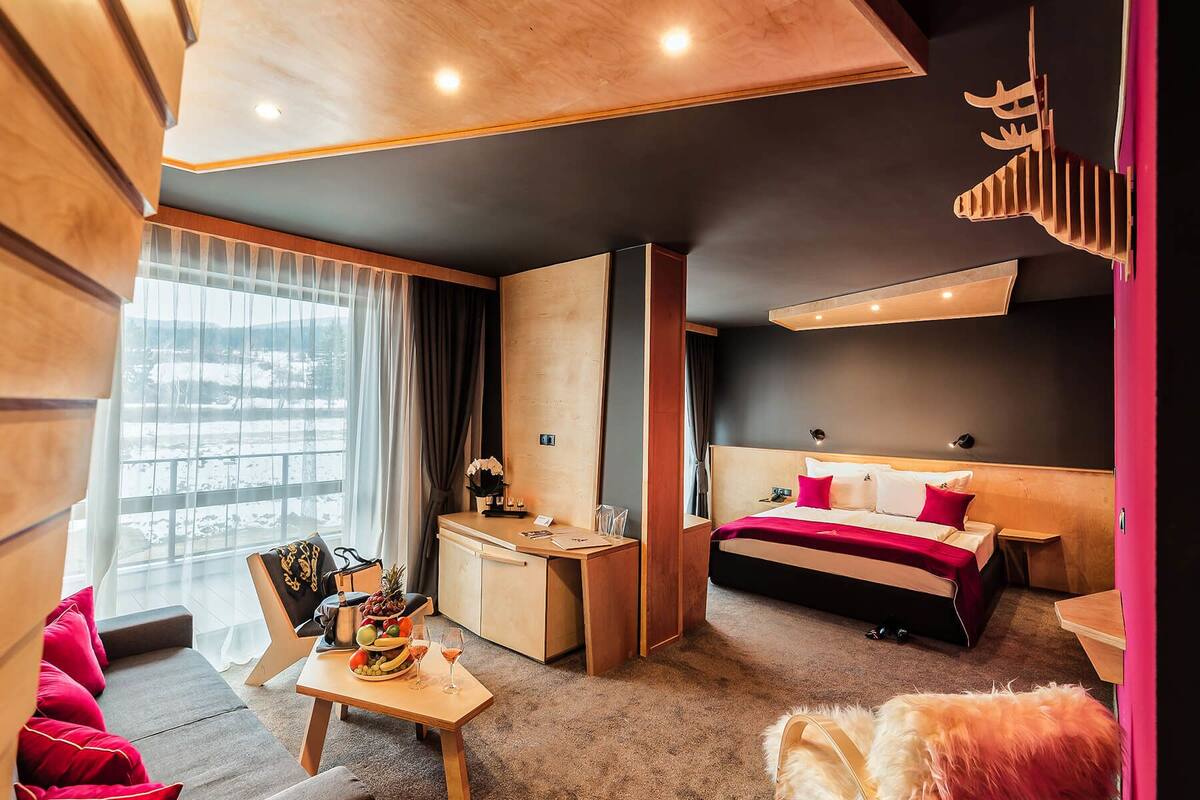 A modern hotel room with a bed, desk, and seating area.