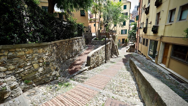 A narrow cobblestone pathway flanked by stone walls and buildings with balconies. - Romantica Mansarda Pisano (Genoa)