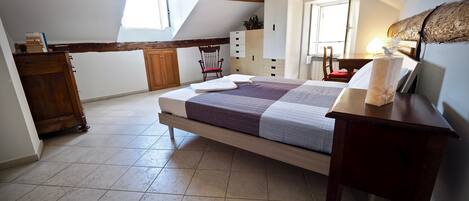A bedroom with a bed, wooden furniture, a window, and a sloped ceiling.