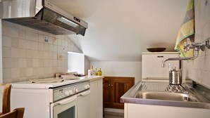 A compact kitchen with a built-in oven, a stove, and a sink. - Romantica Mansarda Pisano (Genoa)