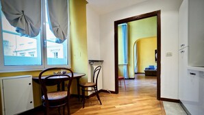 A room with a wooden floor, a dining table with chairs, a radiator, and a window with curtains. - Dimora Lusso delle Vigne (Genoa)