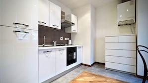 A modern kitchen with white cabinets, a built-in oven, and a wooden herringbone floor. - Dimora Lusso delle Vigne (Genoa)