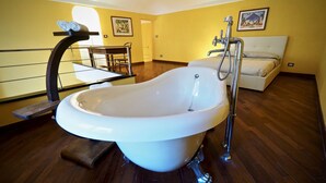 A large, freestanding bathtub in a room with wooden flooring and yellow walls. - Dimora Lusso delle Vigne (Genoa)