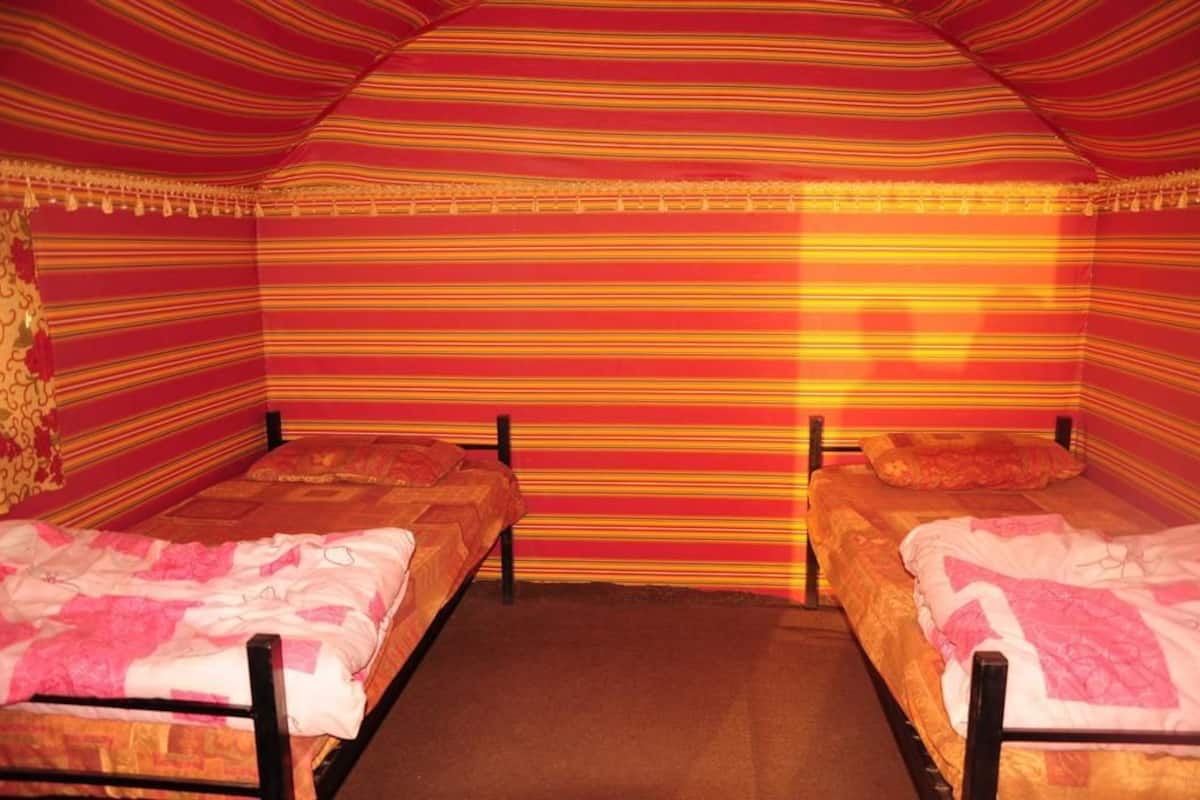 Quarto com duas camas, papel de parede listrado e piso coberto por carpete.