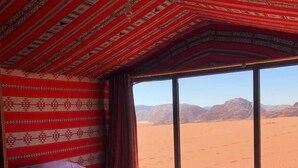Una habitación con una cama, una ventana y vistas al paisaje desértico.