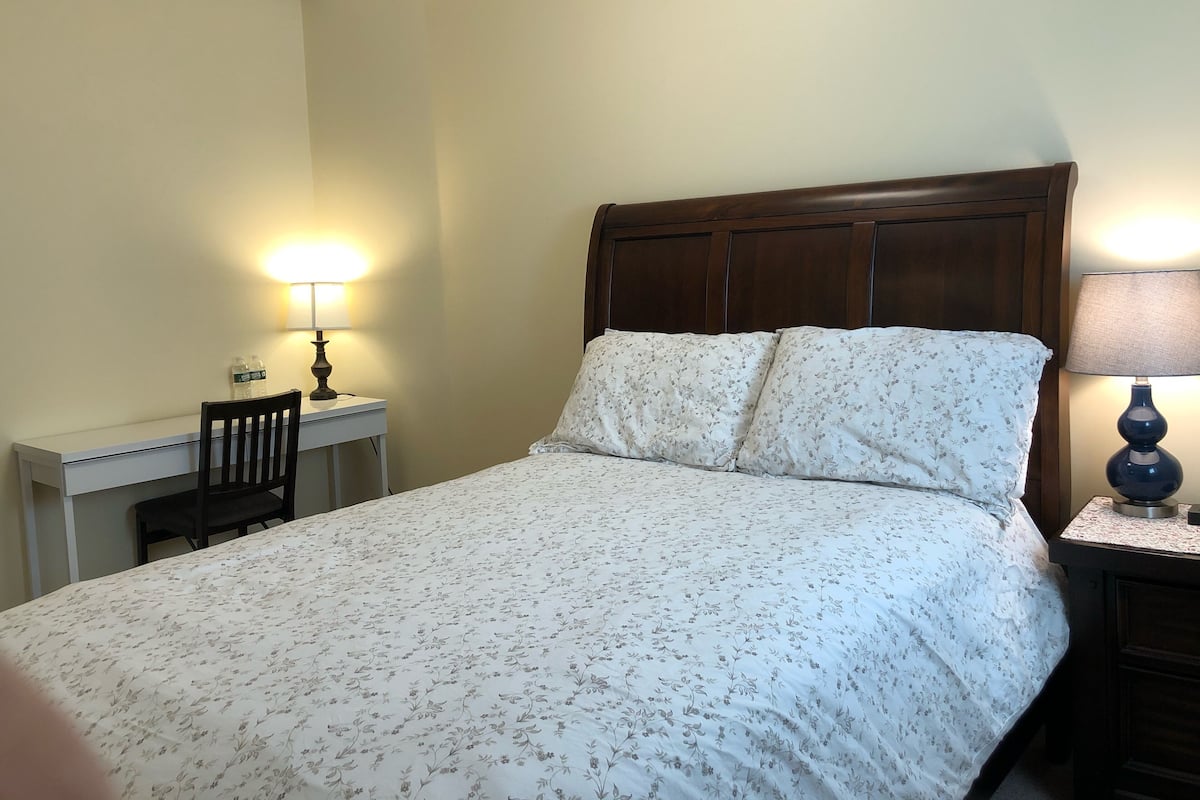 A neatly made bed with floral bedding, a wooden headboard, and two bedside lamps.