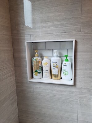 A bathroom shelf with four toiletry bottles. - Tranquil House in Cambridge (Cambridge)
