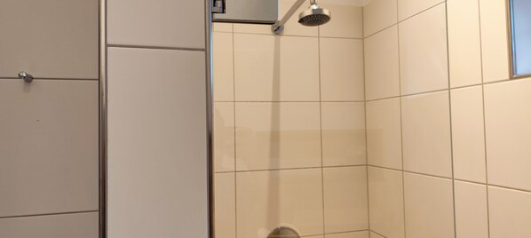 A bathroom with white tiled walls, a shower, and a toilet. - Arena Hotel Waldshut (Waldshut-Tiengen)