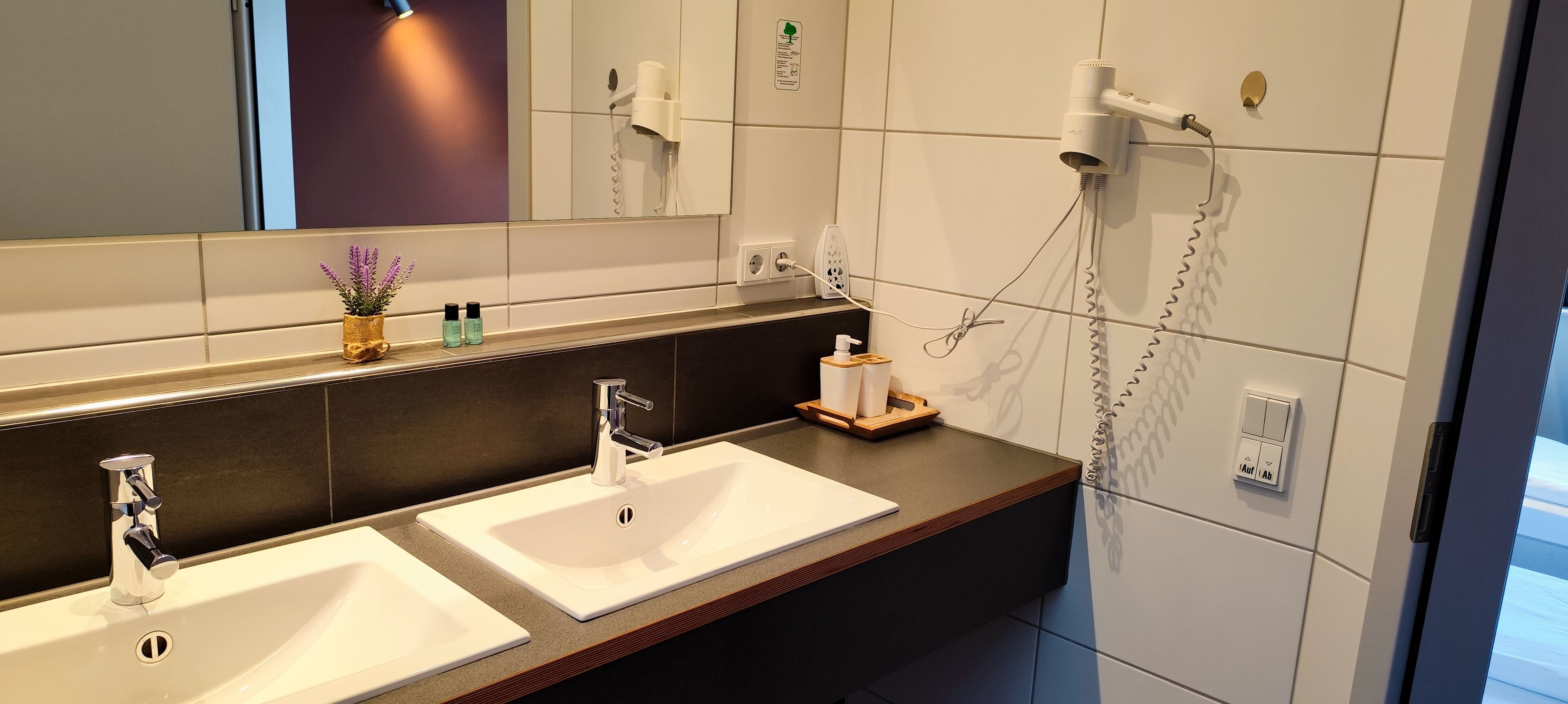Une salle de bain moderne avec deux lavabos, un sèche-cheveux et un miroir.
