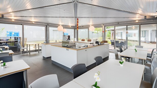 Un espace repas moderne comprenant des tables, des chaises et un îlot central doté d’un évier.