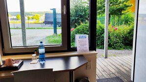 Un comptoir d’accueil d’hôtel avec vue sur un parking et un panneau indiquant l’emplacement de la salle omnisports de Waldshut.
