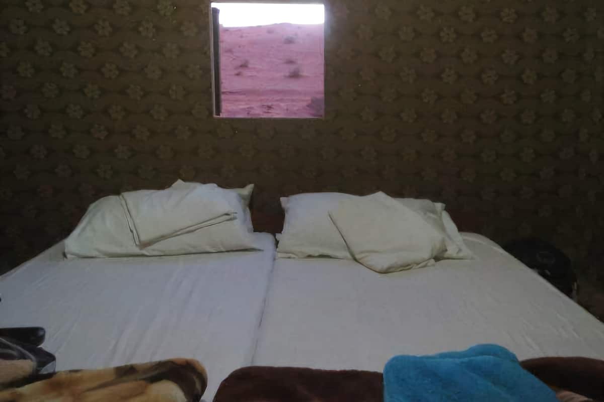 A room with a bed, a window, and a patterned wall.