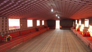 A spacious room with patterned walls, large windows, and a wooden floor. - Wadi Rum Candles Camp (Wadi Rum)