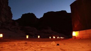 A desert landscape at dusk with illuminated structures and a clear sky. - Wadi Rum Candles Camp (Wadi Rum)