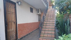 A narrow pathway leading to a brick staircase with a metal railing.