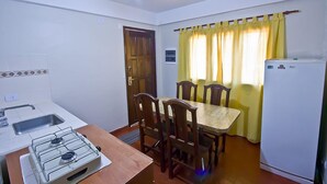 A compact kitchen with a gas stove, sink, and a dining table with chairs.
