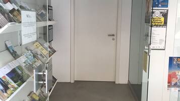 Un couloir avec des vitrines contenant des brochures, une porte fermée et des affiches sur le mur.