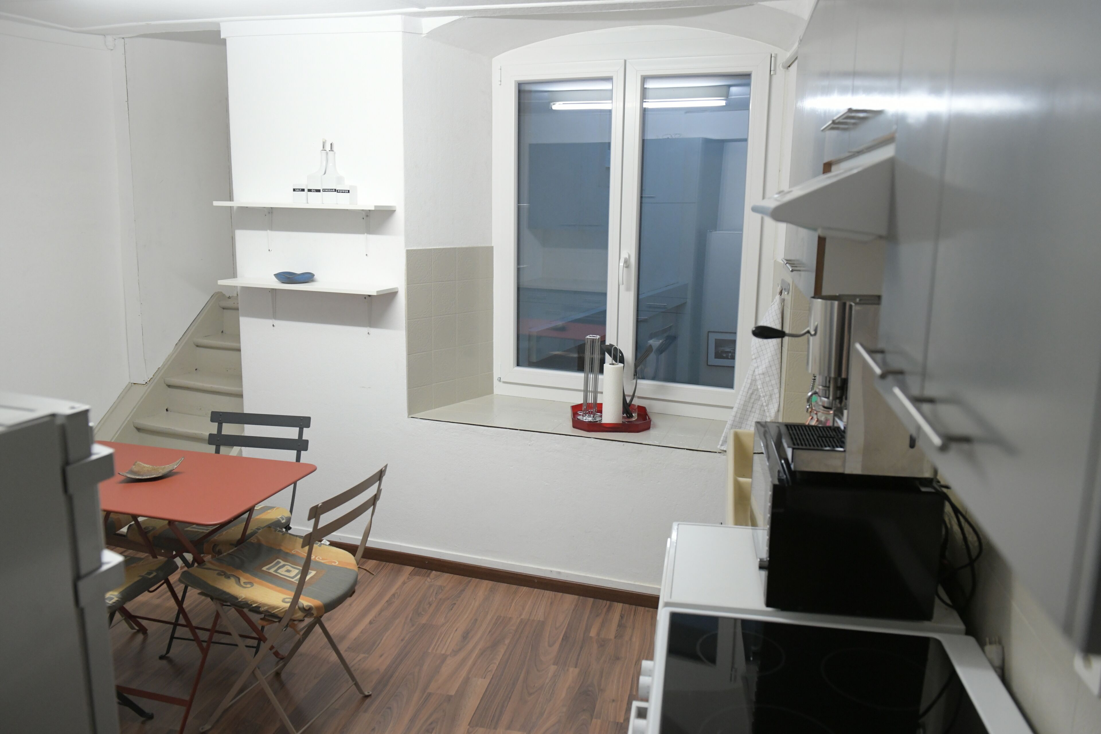 Cocina compacta con zona de comedor, ventana y un refrigerador pequeño.
