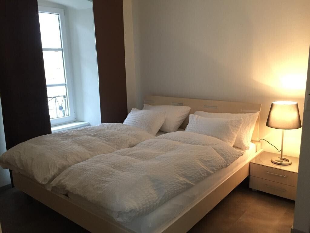 Un lit double bien fait, avec une tête de lit, une table de chevet avec une lampe et une fenêtre avec des rideaux.