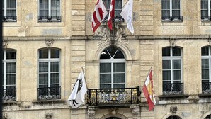 A historic building with a prominent clock, multiple flags, and ornate architectural details. - Albergo Diffuso (Porrentruy)