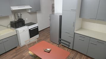 Une cuisine de taille réduite avec des meubles gris, un four à micro-ondes, un lave-vaisselle et un réfrigérateur.