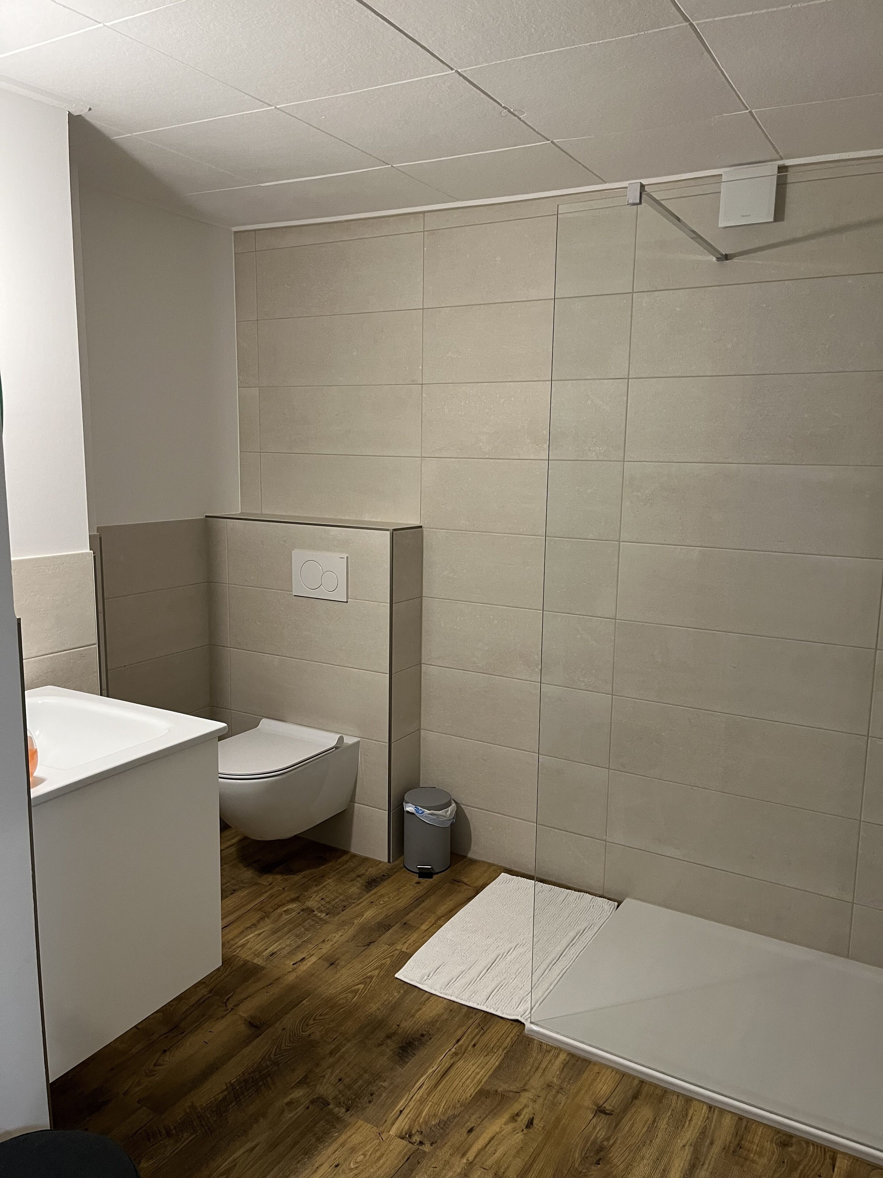Une salle de bain comprenant des toilettes, un lavabo, une poubelle et un espace douche.