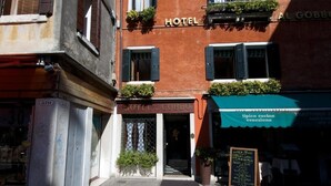 A hotel with a sign reading "HOTEL AL GOBBO" and a nearby restaurant with a sign "tipica cucina veneziana." - Albergo Al Gobbo   (Venice)