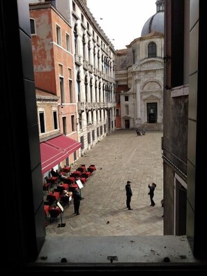 A courtyard with a red awning, a fountain, and a building with classical architecture. - Albergo Al Gobbo   (Venice)