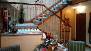 A staircase with ornate metal railings, a wooden handrail, and a carpeted floor. - Albergo Al Gobbo   (Venice)
