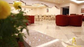 A hotel lobby with a long reception desk, red seating area, and a tiled floor. - Amman Palace Hotel (Amman)
