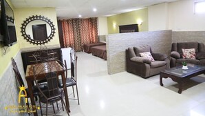 A hotel lobby with a dining area, two sofas, and a television. - Amman Palace Hotel (Amman)