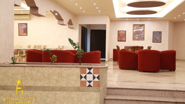 A hotel lobby with a reception desk, red sofas, and framed artwork on the walls. - Amman Palace Hotel (Amman)