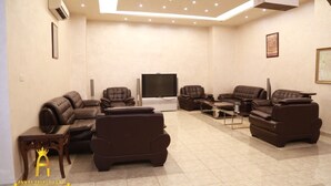 A modern living room with leather sofas, a flat-screen TV, and a coffee table. - Amman Palace Hotel (Amman)