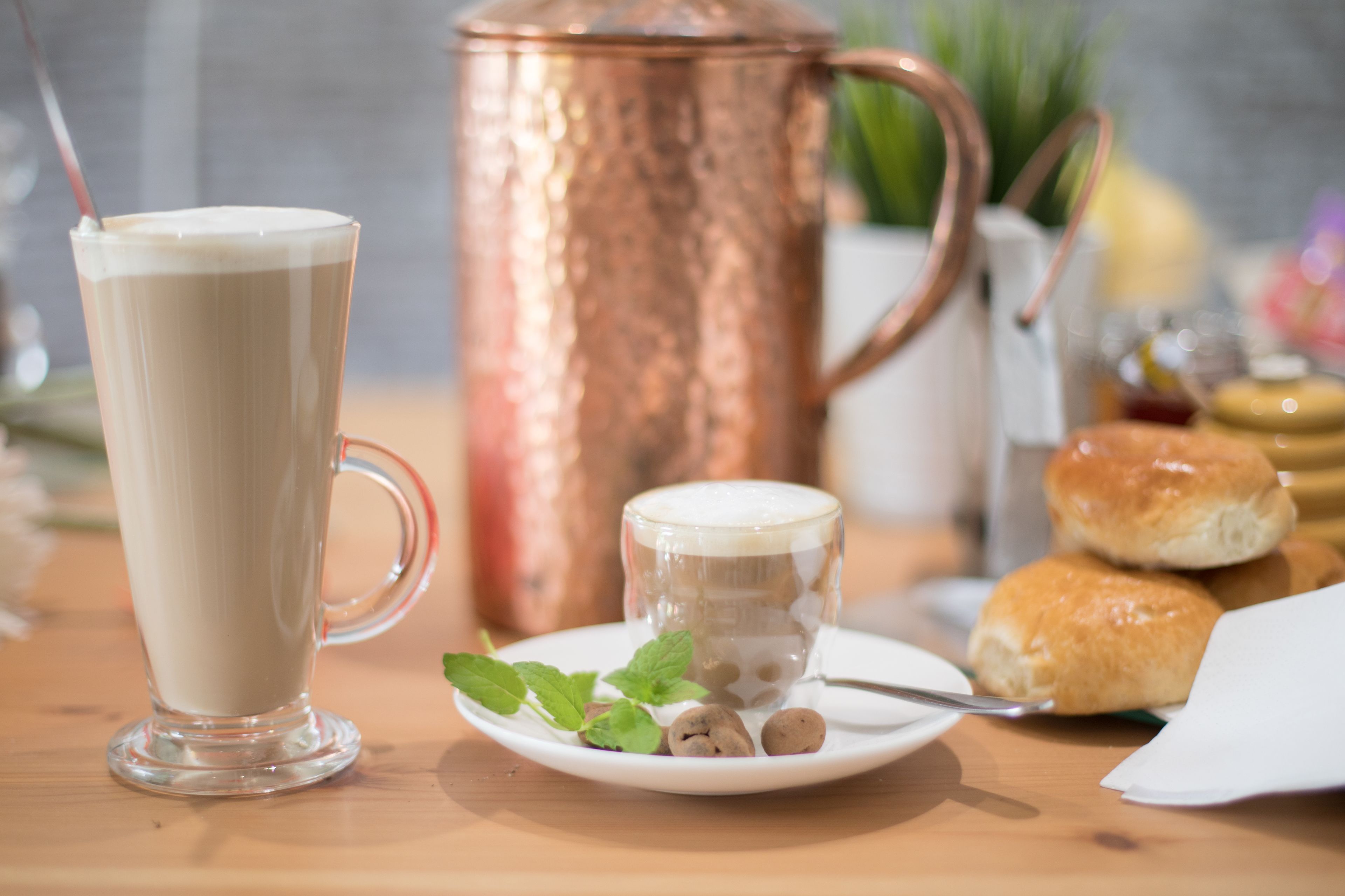 Taula amb un got gran de cafè, una tassa més petita i un plat amb galetes.